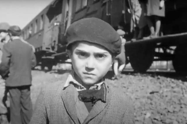 <p>The face of a young survivor. Behind him stands the train on which he has been incarcerated for the past week, along with some 2,500 of his fellow Jews</p>
